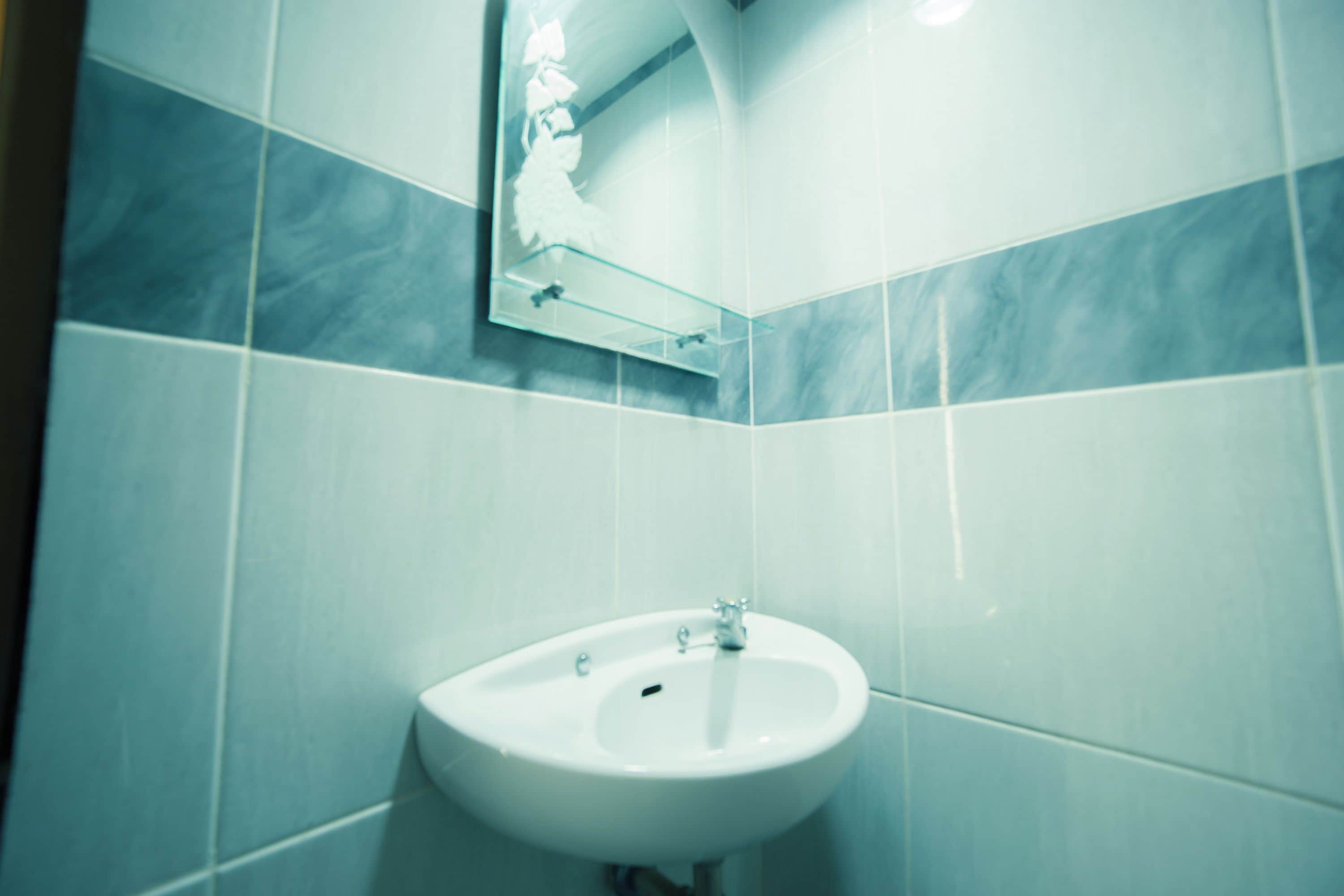 Een badkamer met een witte wasbak, een spiegel en betegelde wanden.