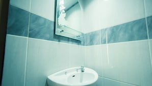 Een badkamer met een witte wasbak, een spiegel en betegelde wanden.