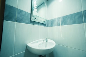 A bathroom with a white sink, a mirror, and tiled walls. - Rehat at Villa Cemara Kembar (Kabupaten Bandung)