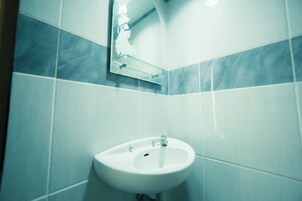 A bathroom with a white sink, a mirror, and tiled walls.