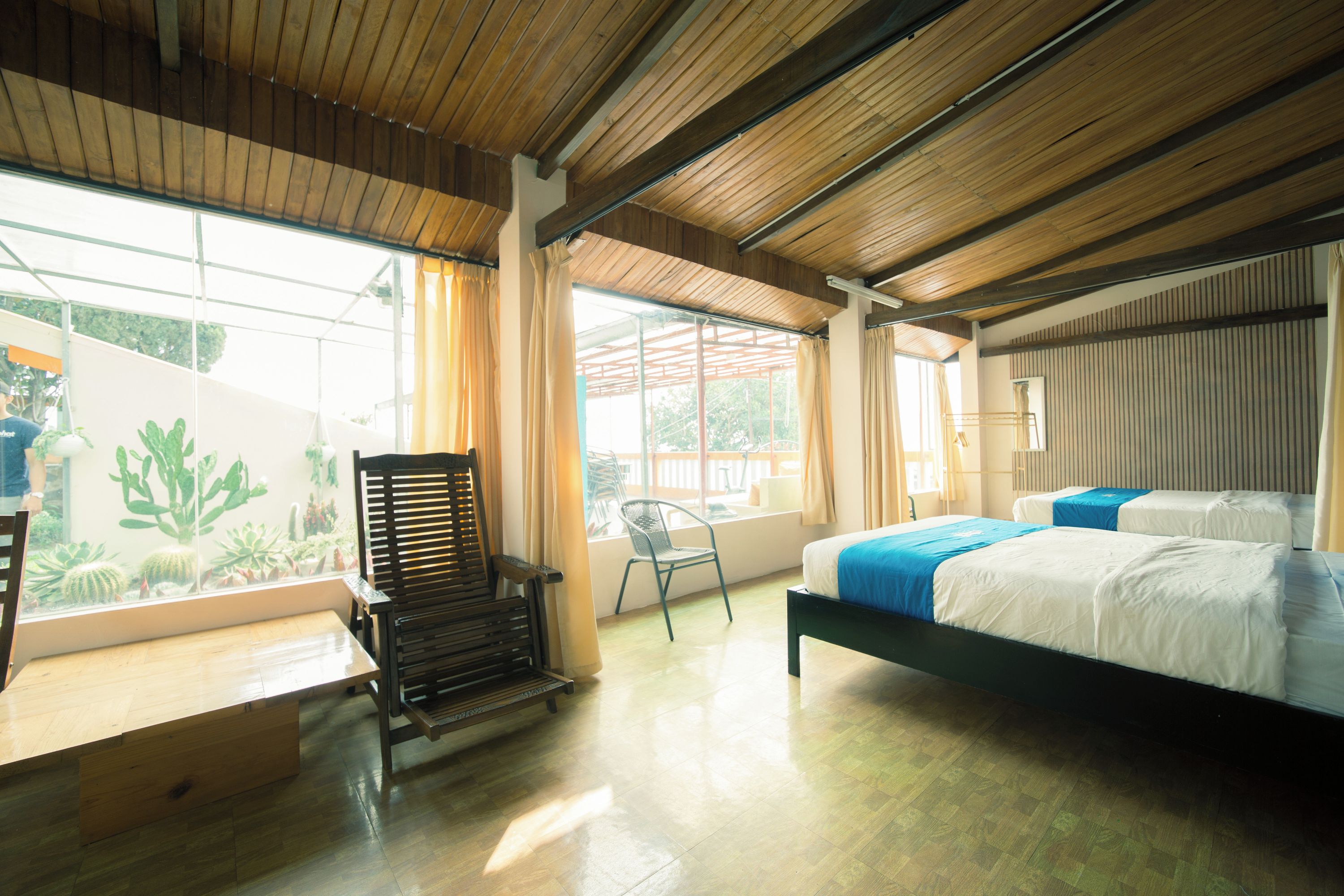 Una habitación con cama, una silla, una mesa y una ventana con cortinas.