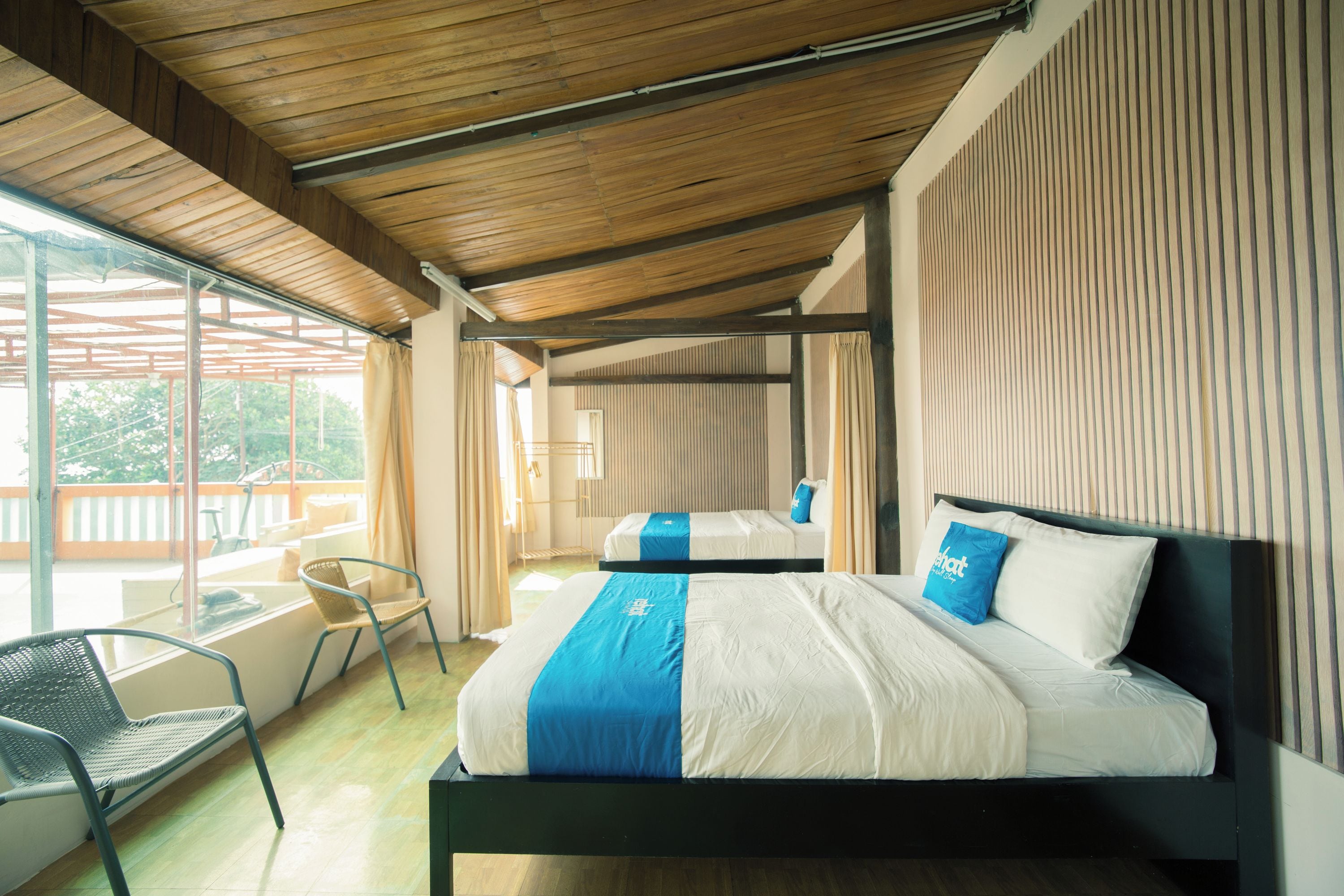 Una habitació d'hotel moderna amb un llit gran, una cadira i vistes a l'exterior.