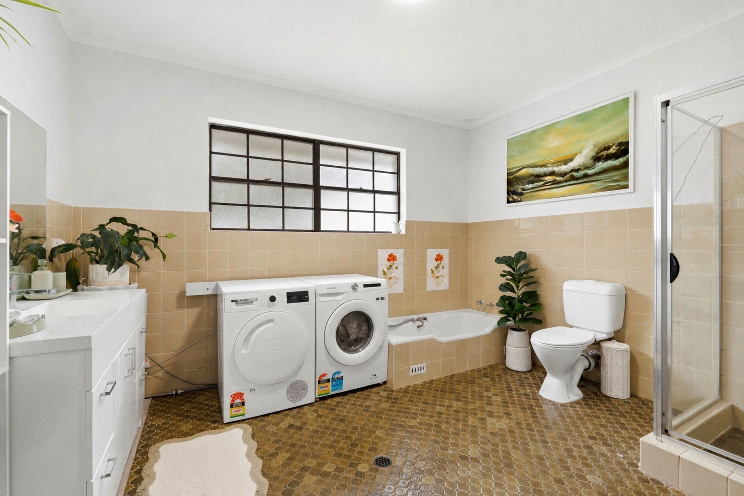 A bathroom with a washing machine, a bathtub, a toilet, and a shower.