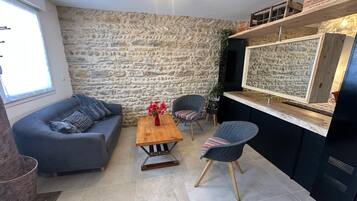 Een moderne woonkamer met een stenen muur, een bank, een salontafel en een stoel.