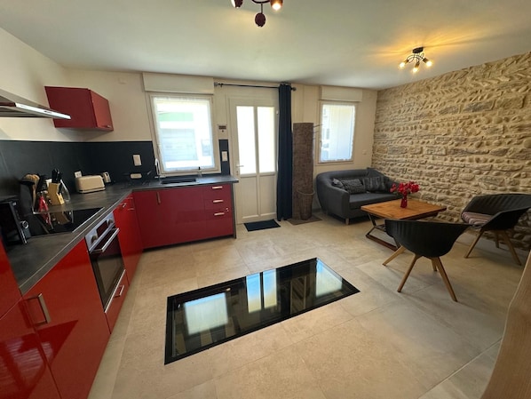 A compact living space with a kitchenette, a dining area, and a seating area with a stone wall.
