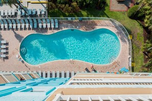 Una piscina de borde curvo, rodeada de sillas de descanso y una terraza.