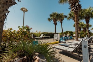 Zona de piscina amb gandules, palmeres i un fanal.