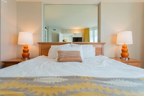 Habitación de hotel con cama, dos lámparas de noche, un espejo y vista al interior de la habitación.