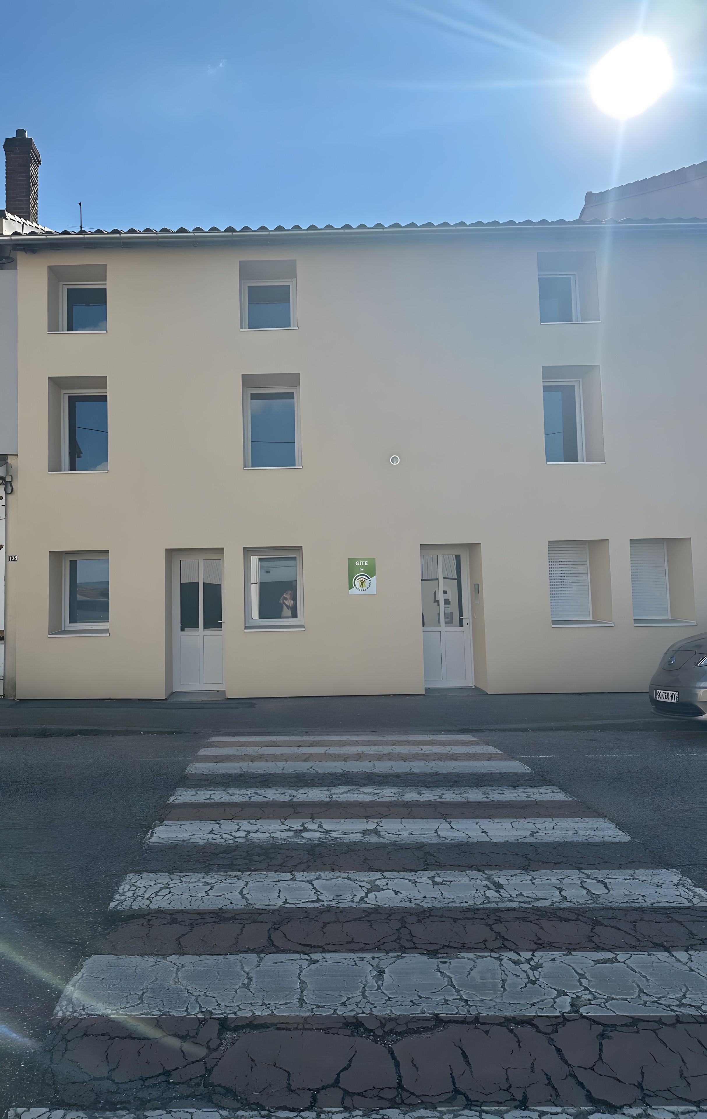 A building with a flat facade, multiple windows, and a pedestrian crossing in front.