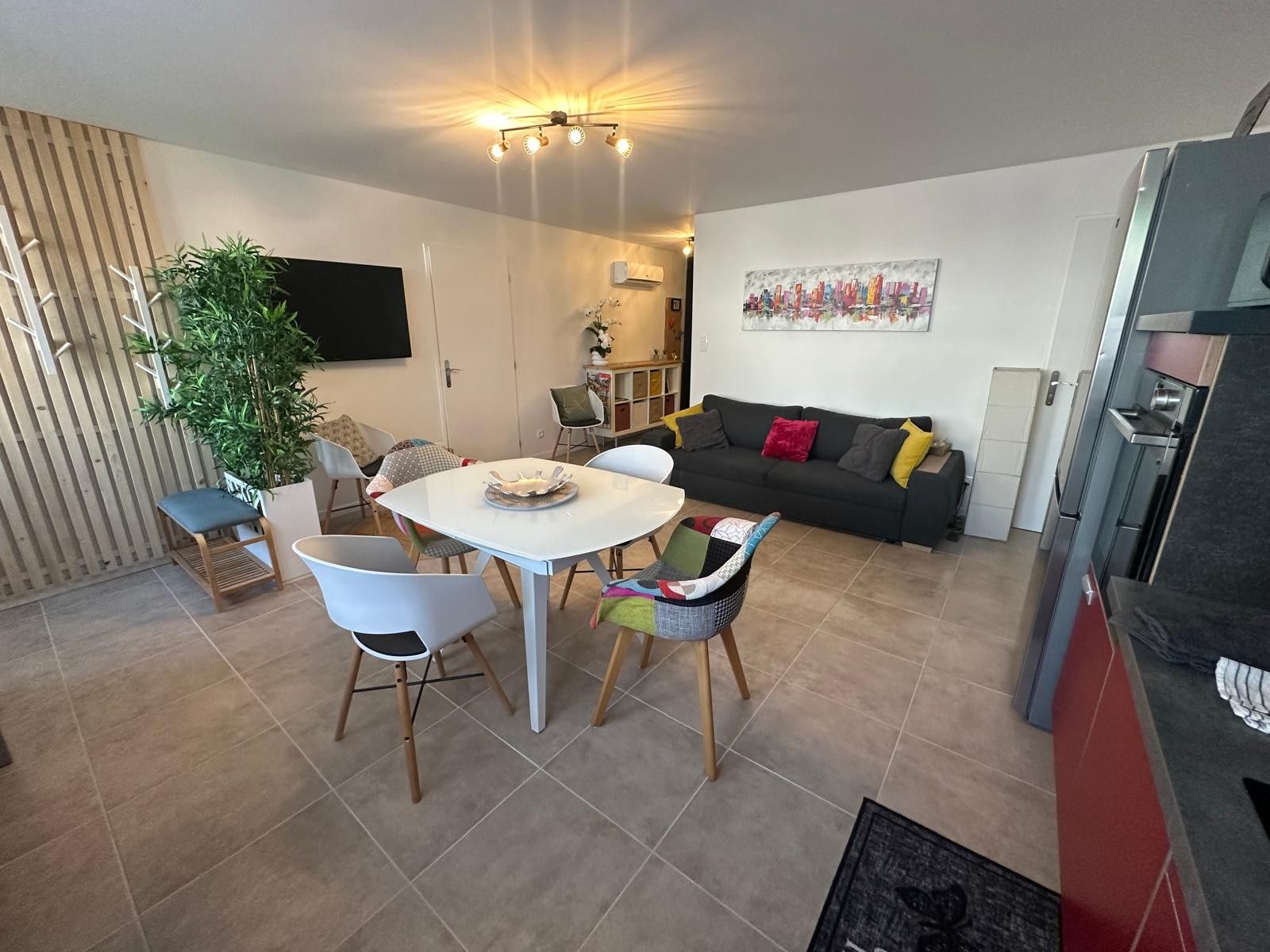 Un espacio de estar moderno con comedor, sofá, televisor y cocina.
