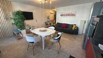 Un espacio de estar moderno con comedor, sofá, televisor y cocina.