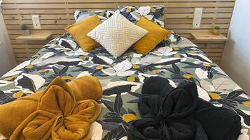 Un lit avec une couvre-lit à motifs floraux, deux oreillers et deux serviettes.