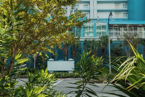 Een hotel met een blauwe gevel, een glazen constructie en een omheinde tuin.