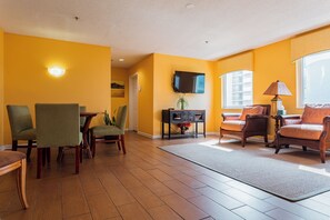 A living room with a TV, sofa, chairs, and a dining area with a table and chairs. - North Myrtle Beach | Marsh Escape | Pool & Beach Access | 2BR Villa (North Myrtle Beach)