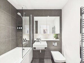 Et moderne badeværelse med badekar, toilet og håndvask.