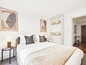 Une chambre d’hôtel comprenant un lit, des tables de chevet, une armoire et un miroir.