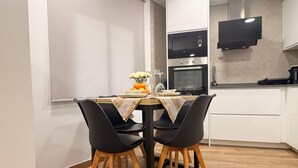 A modern kitchen with white cabinets, a microwave, an oven, and a flat-screen TV mounted above the counter. - Apartment 'Cullera' with Mountain Views, Wi-Fi, and Air Conditioning (Cullera)