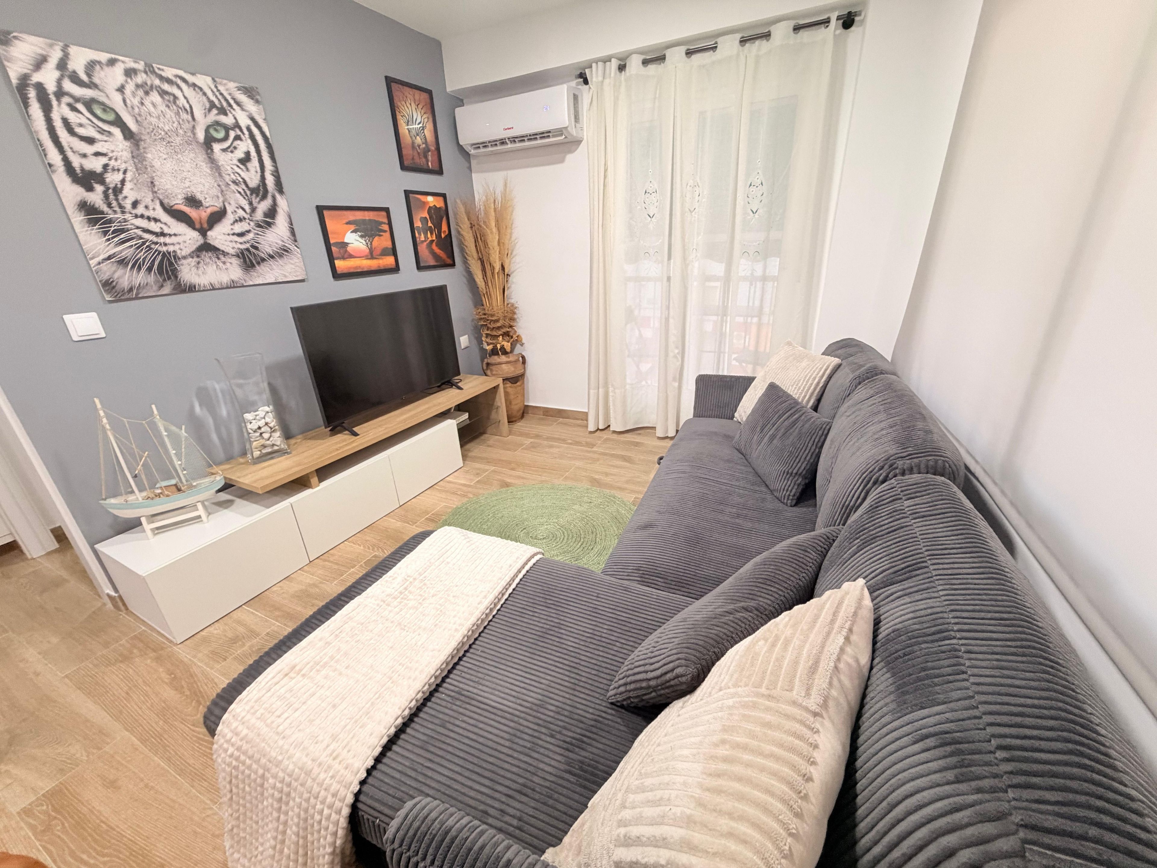 Una sala de estar moderna con un sofá gris, un televisor de pantalla plana y obras de arte en la pared.
