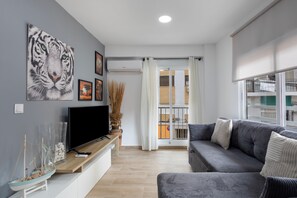 Un salon moderne avec un téléviseur à écran plat, un canapé gris et une grande œuvre d’art représentant un tigre accrochée au mur.