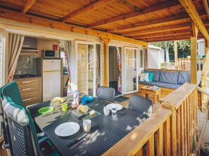 A covered outdoor dining area with a table set for two, chairs, a sofa, and a wooden deck. - Spacious Group Coastal Stay (Brtonigla)
