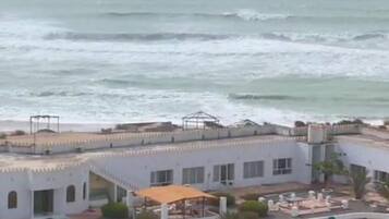 Een hotel aan de kust met een zwembad, ligbedden en uitzicht op zee.