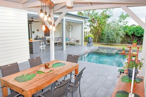 Eine Außenpatio mit Pool, Esstisch, Stühlen und einer Sitzecke mit Blick auf den Garten.