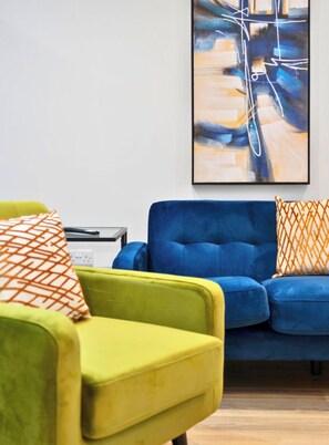 A room with a blue sofa, a yellow armchair, and a painting on the wall. - 2 Bed Flat in Airdrie | Sleeps 4 | Parking (Airdrie)
