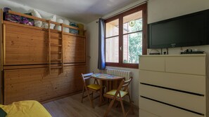A room with a wooden bunk bed, a table with chairs, a radiator, and a television on a cabinet. - Cabin studio with nature view (Orcières)