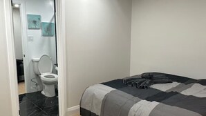 Quarto com cama, banheiro com vaso sanitário e porta para outro cômodo.