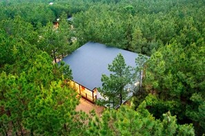A square building surrounded by dense forest, with a flat roof and a visible entrance. - Luxury Cabin with Private Hot Tub & Sauna Getaway in Broken Bow, Oklahoma (Broken Bow)