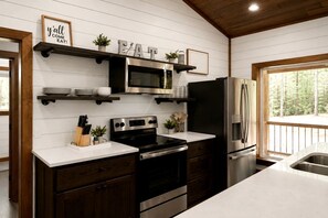 A modern kitchen with white cabinetry, stainless steel appliances, and a wooden ceiling. - Luxury Cabin with Private Hot Tub & Sauna Getaway in Broken Bow, Oklahoma (Broken Bow)