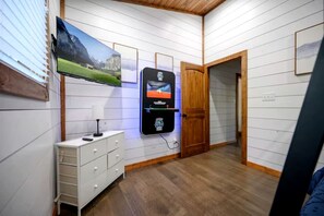 A room with a mounted television, a wooden door, and a white dresser. - Luxury Cabin with Private Hot Tub & Sauna Getaway in Broken Bow, Oklahoma (Broken Bow)