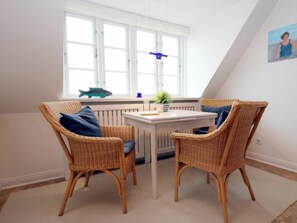 Ein Zimmer mit zwei Korbstühlen, einem kleinen Tisch und einem Fenster mit Blick nach draußen.