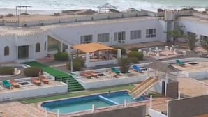 A coastal hotel with a pool, lounge chairs, and a view of the ocean. - Arabian Sea Hotel & Chalets - Two-Bedroom Chalet 2 (Aş Şulayb)