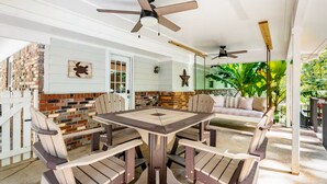 Eine Terrasse mit Esstisch, Stühlen, einer Schaukel und Deckenventilatoren.