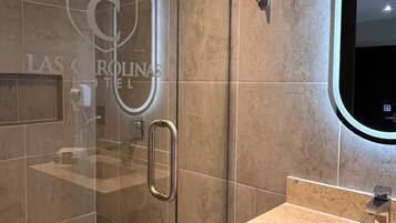 A modern bathroom with a glass-enclosed shower, a vanity with a sink, and a large mirror.