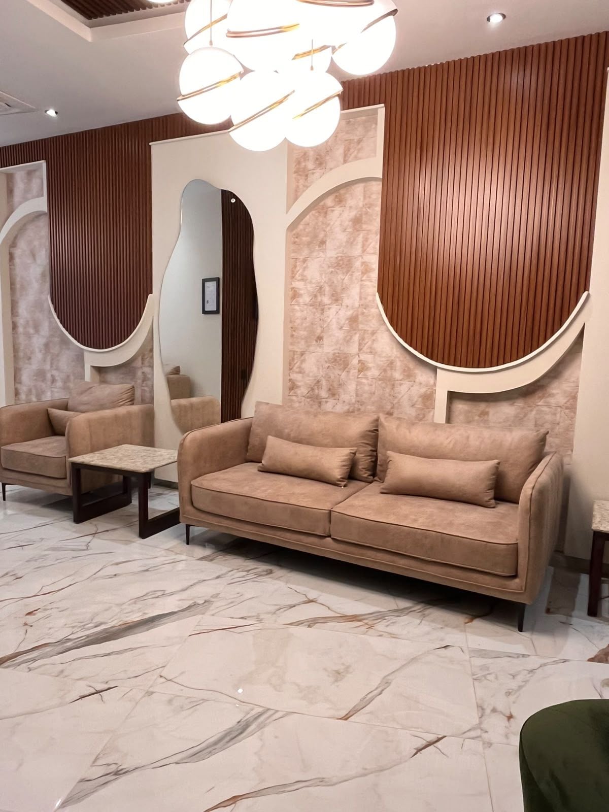 A modern interior with a sofa, armchairs, a small table, and a decorative light fixture.