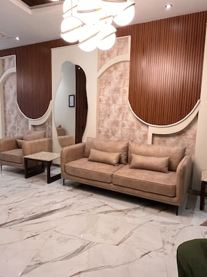A modern interior with a sofa, armchairs, a small table, and a decorative light fixture. - Hotel Las Carolinas (Huejutla de Reyes)