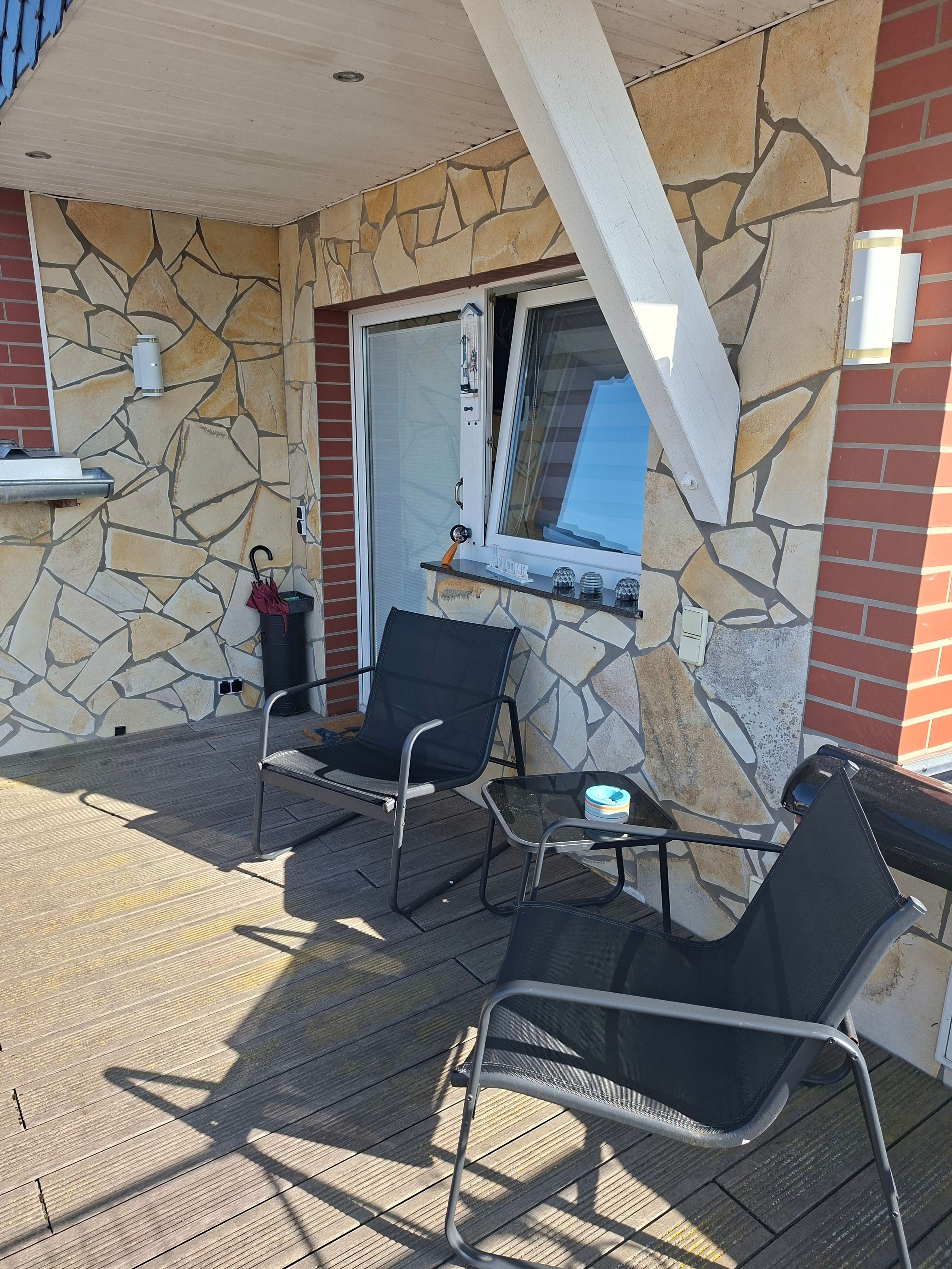 Eine Terrasse mit zwei Stühlen, einem Tisch und einem Fenster mit Blick.