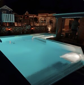 A swimming pool with a stone wall and a covered area with a bench. - Apartment “Pool Oasis” with Pool, Terrace, and Wi-Fi (Colbitz)
