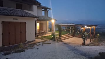 A building with a covered patio area, a gravel driveway, and a view of the landscape.
