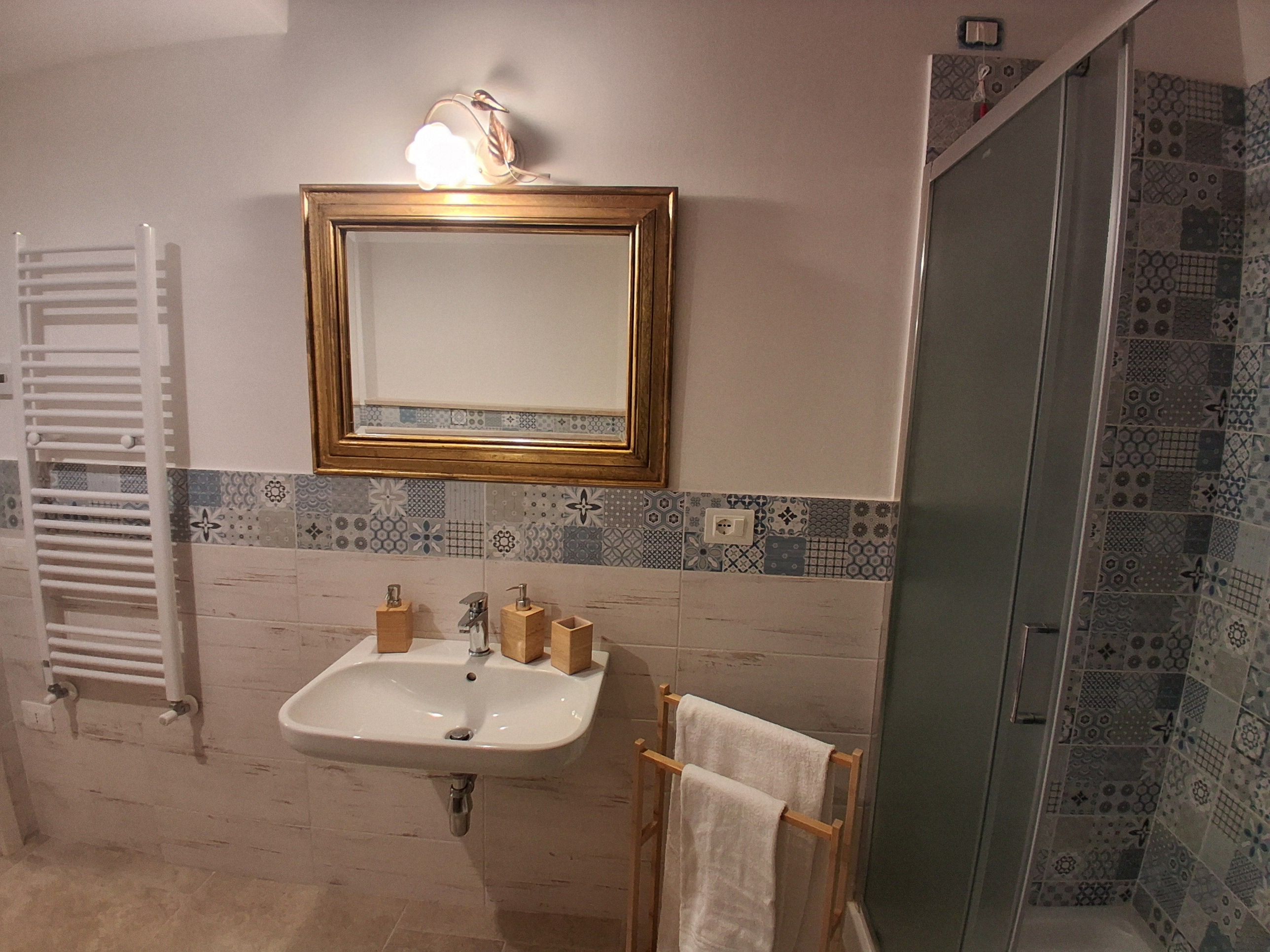 Ein Badezimmer mit Waschbecken, Spiegel, Handtuchhalter und Dusche.