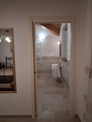 A hallway leading to a bathroom with a white sink, towel rack, and a mirror.