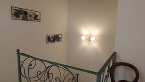 A staircase with a metal railing and a wall-mounted light fixture. - Buon Vento (Camerino)