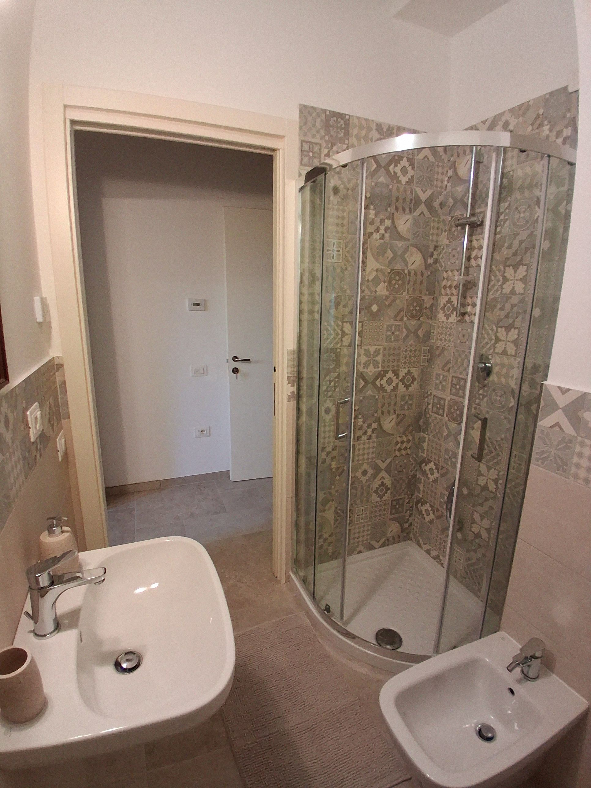 Ein Badezimmer mit einer Duschkabine, einem Waschbecken und einem Bidet.