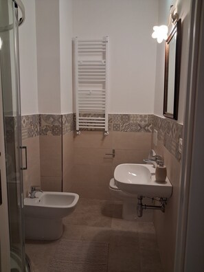 A bathroom with a bidet, a sink, and a towel rack.