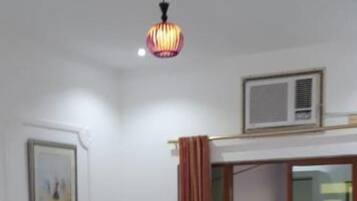 Een hotelkamer met een bed, bureau, stoel, kledingkast en een plafondlamp.