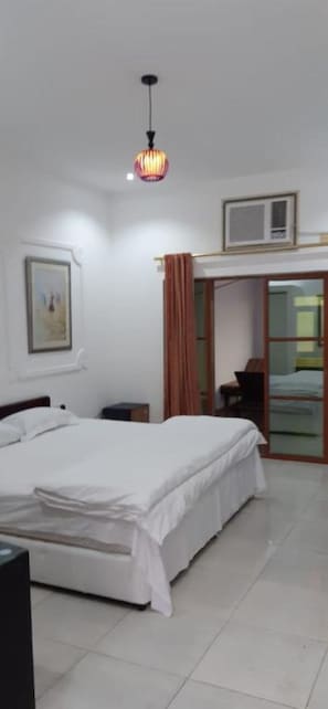 A hotel room with a bed, a desk, a chair, a wardrobe, and a ceiling light.