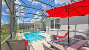 A covered outdoor area with a pool, seating, and a red umbrella. - Private Pool Paradise, Soaring Ceilings, Open Spaces & Fl Resort-Style Charm (Davenport)