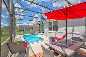 A covered outdoor area with a pool, seating, and a red umbrella. - Private Pool Paradise, Soaring Ceilings, Open Spaces & Fl Resort-Style Charm (Davenport)